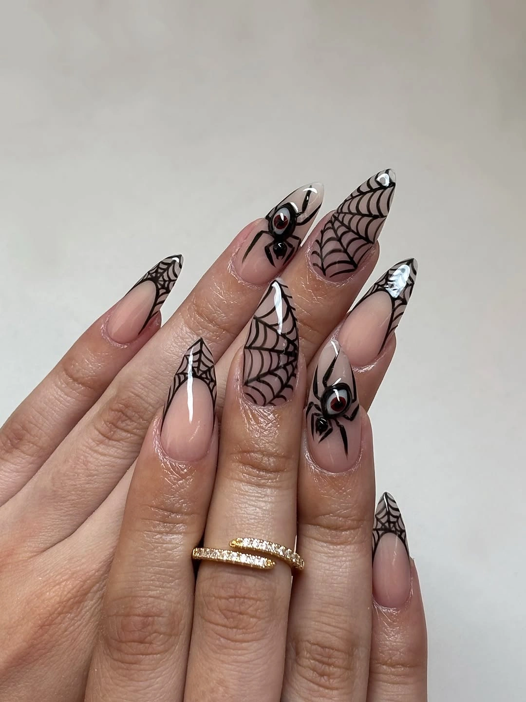 Long stiletto nails with black spiderwebs over pale bases