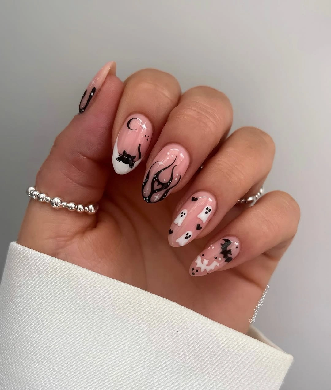 Pale pink almond nails with tiny black ghosts and dots