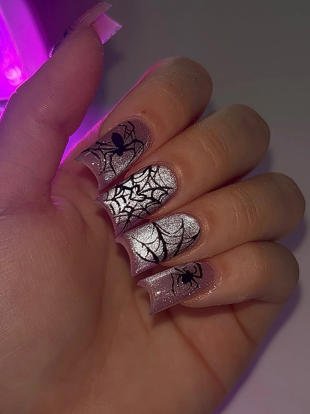 Long square nails with black webs over sheer pink and purple