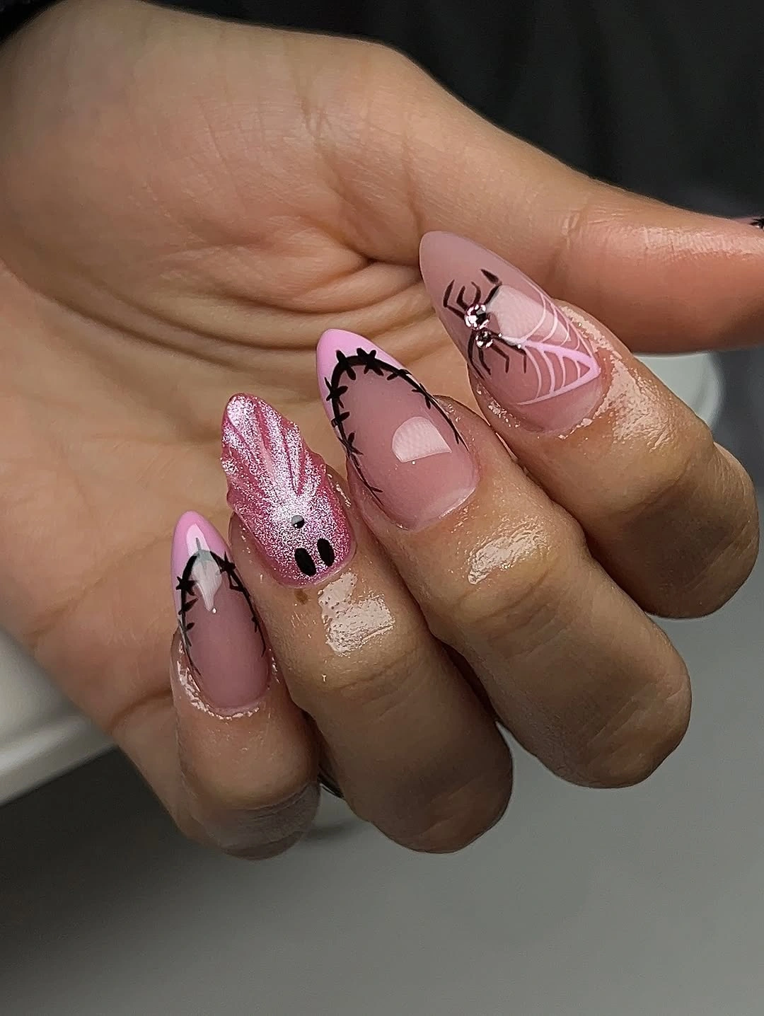 Pink almond nails with black web and stitched Halloween details
