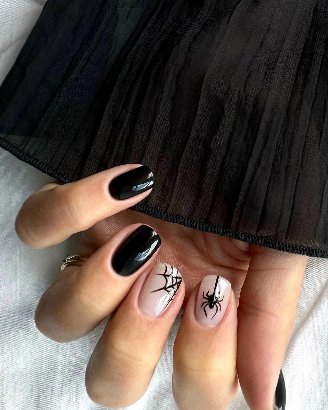 Short glossy black nails with white spiderweb accents