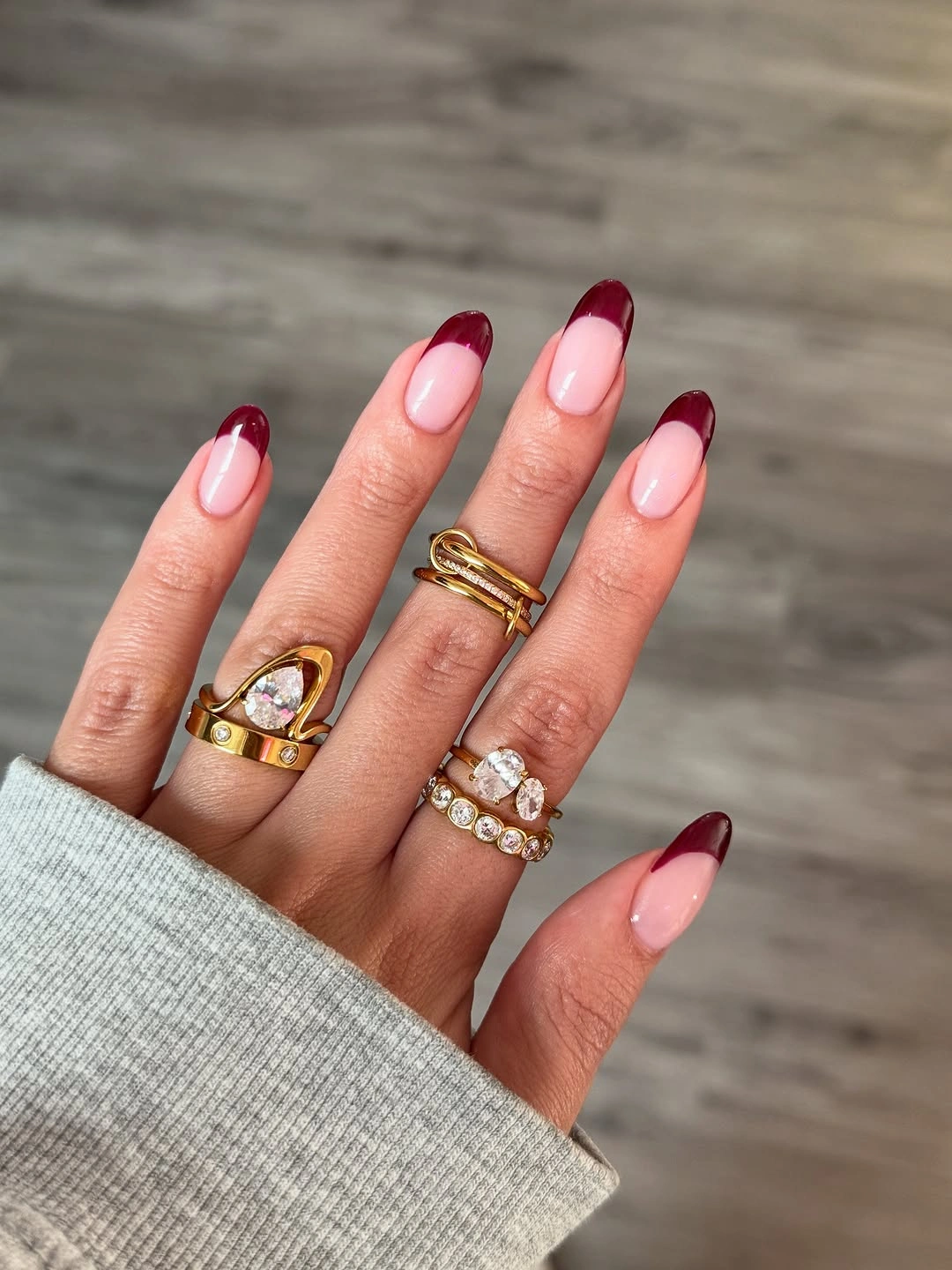 Nude almond nails with slim maroon tips and tiny heart detail