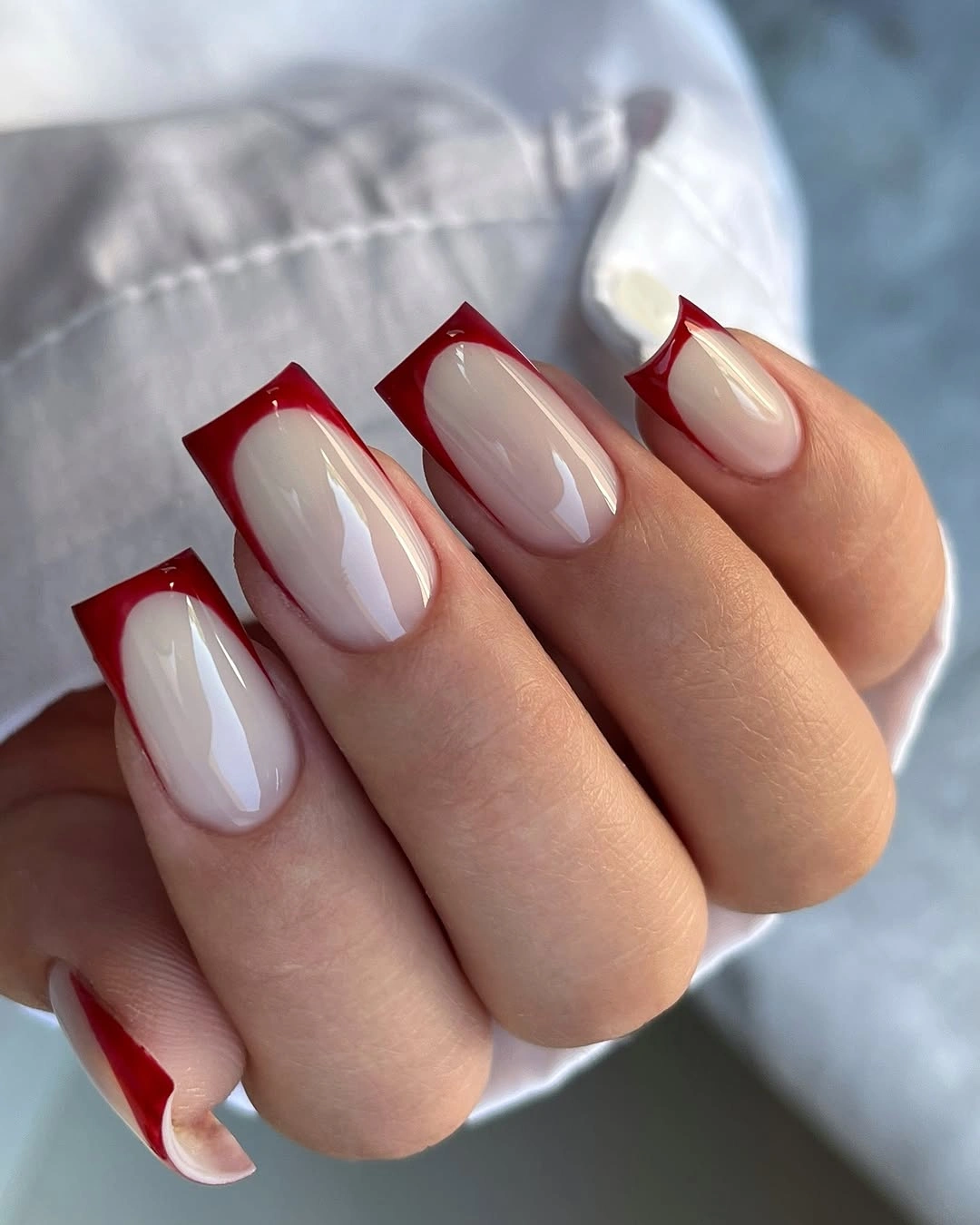 Long square nails with nude centers and red outlined tips