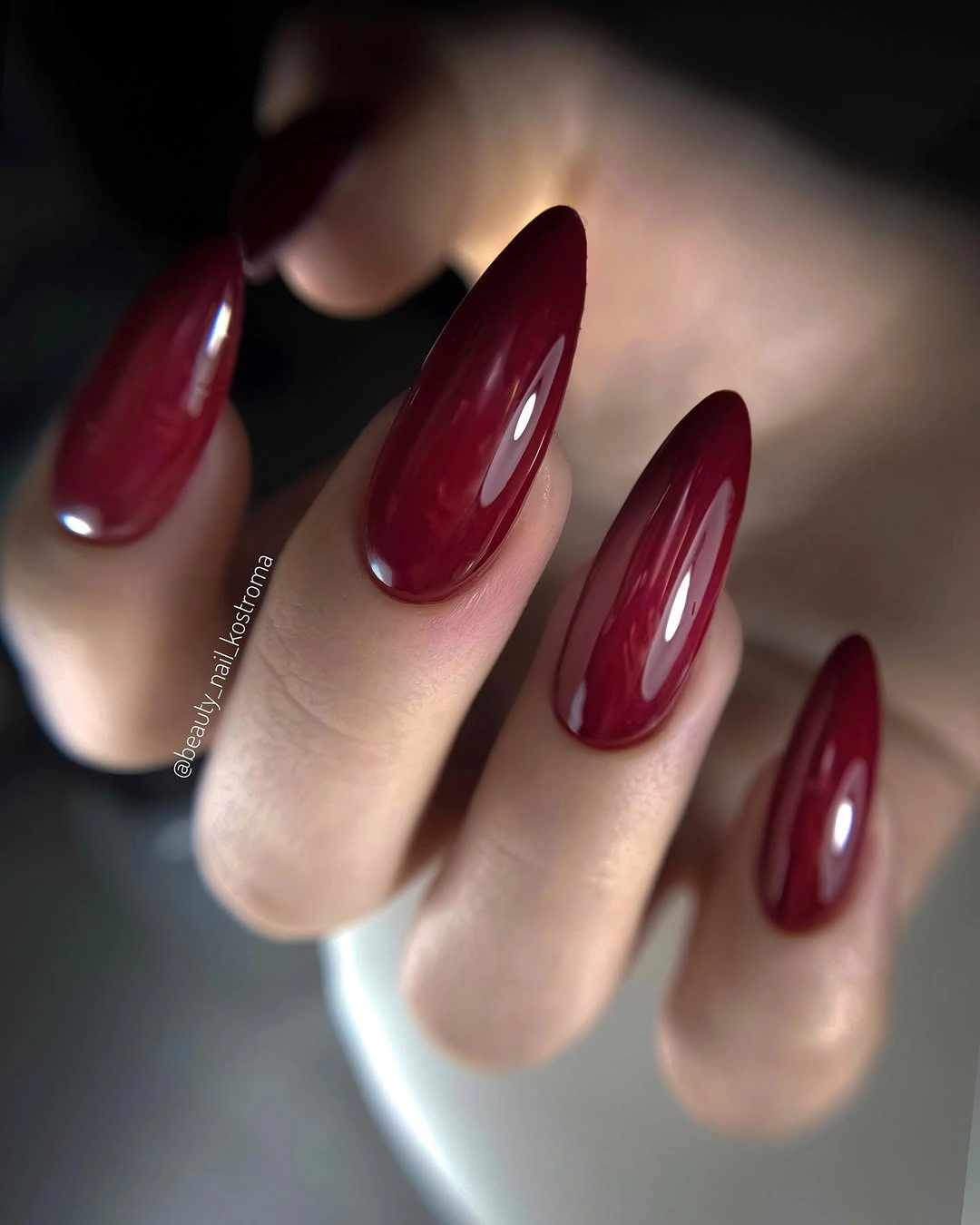 Long glossy maroon almond nails in a uniform single color