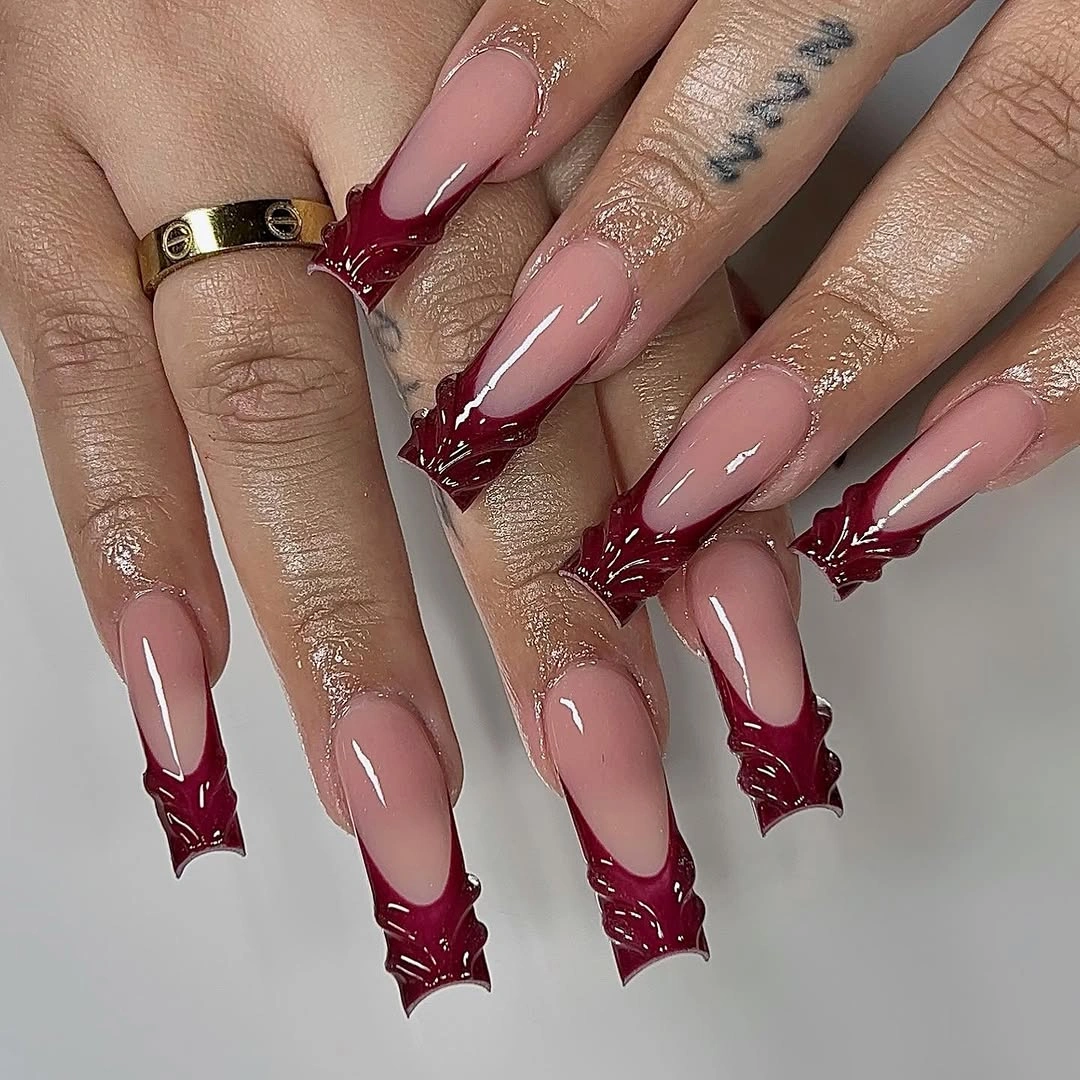 Long nude almond nails with sculptural maroon starburst tips