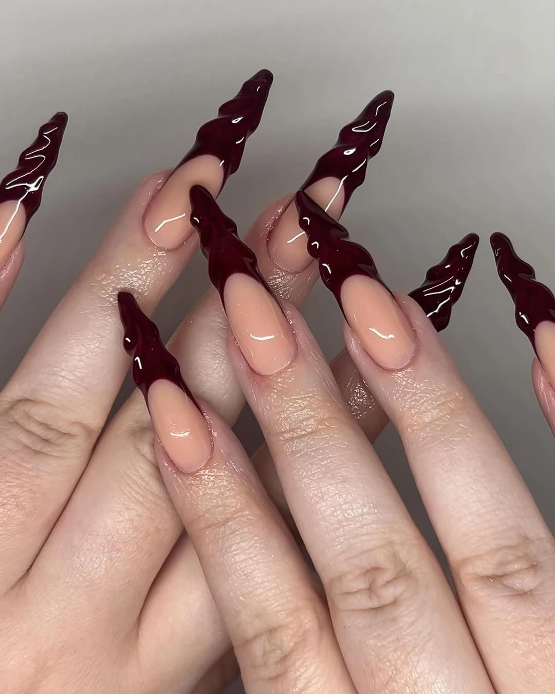 Long nude almond nails with thick glossy burgundy sculptural tips