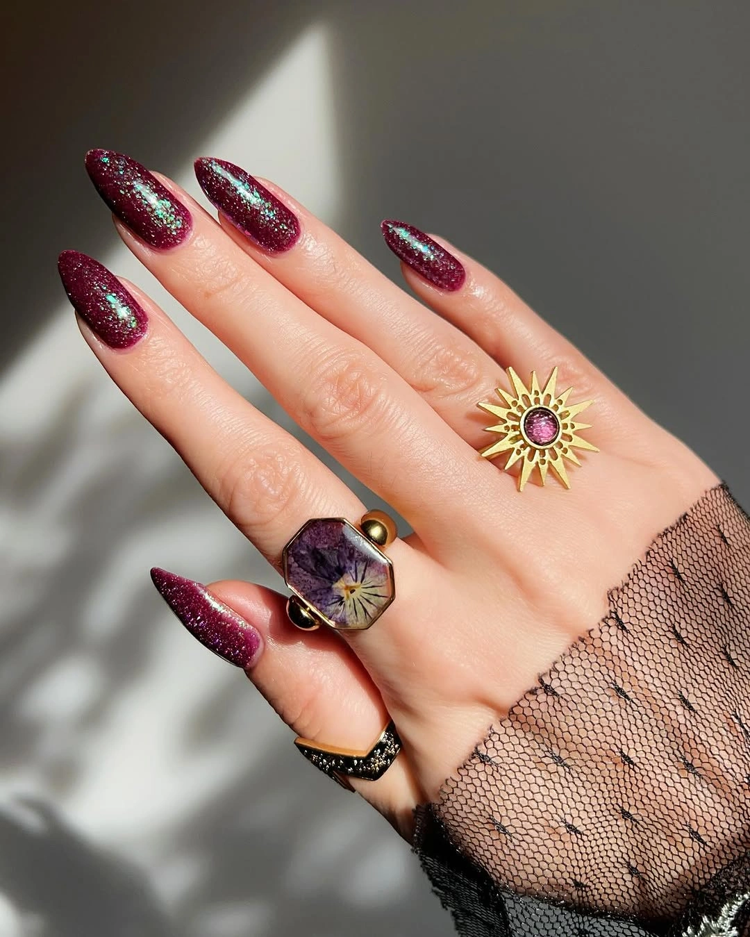 Long maroon almond nails with fine multicolor shimmer at tips