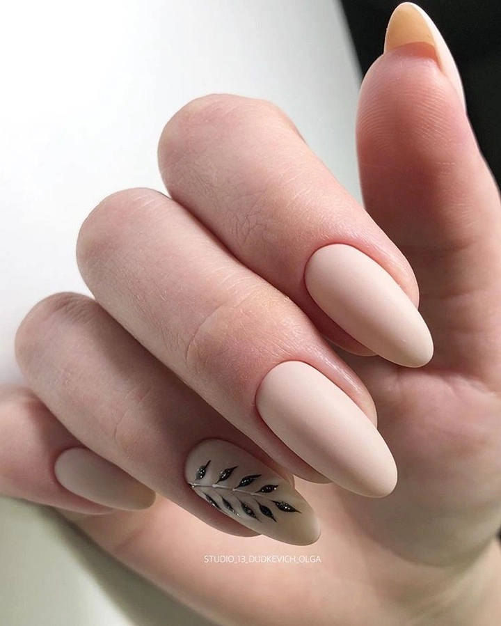 Soft peach almond nails with a small black leafy branch