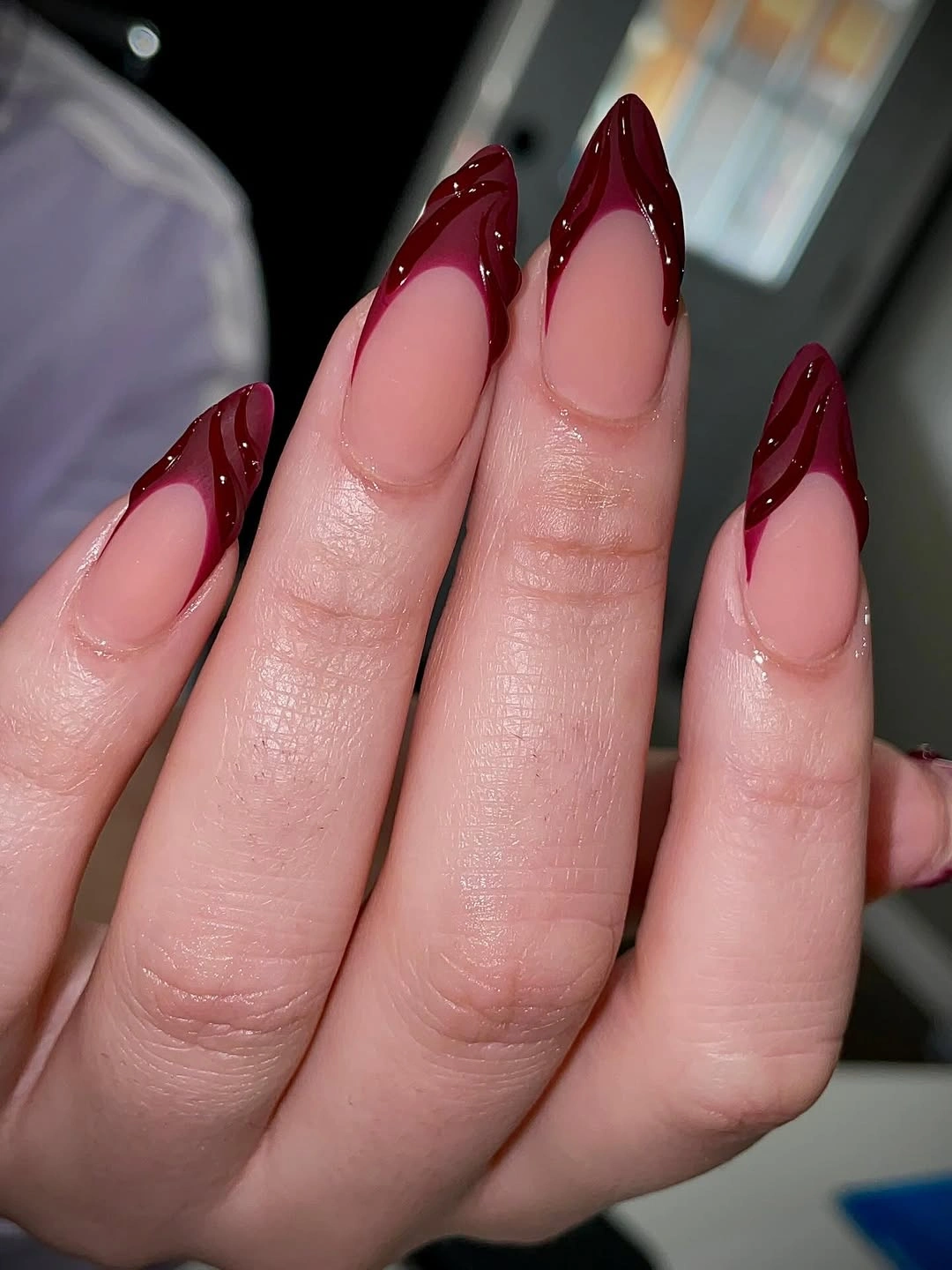 Nude almond nails with glossy burgundy chevron French tips