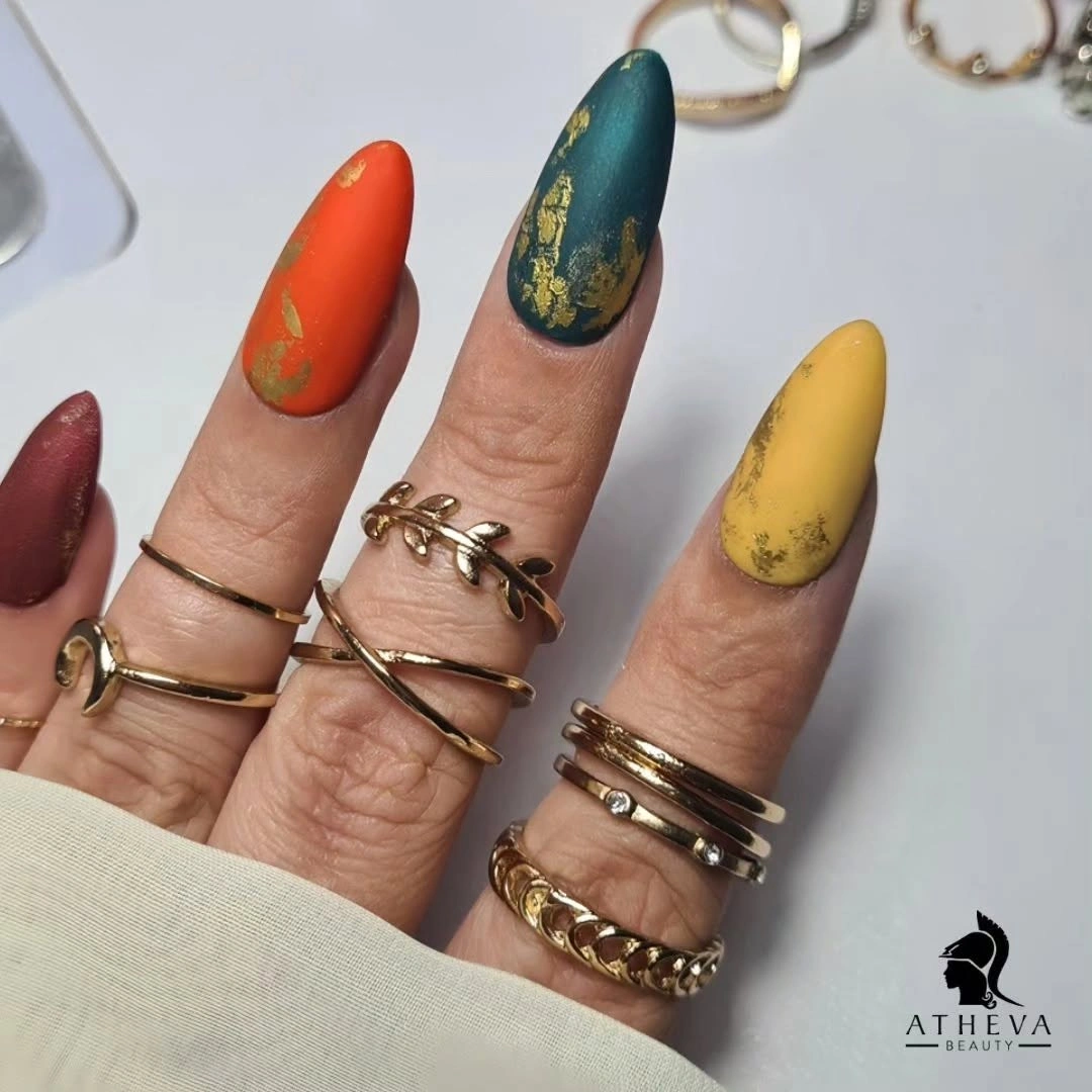 Almond nails in jewel tones with fine gold leaf accents