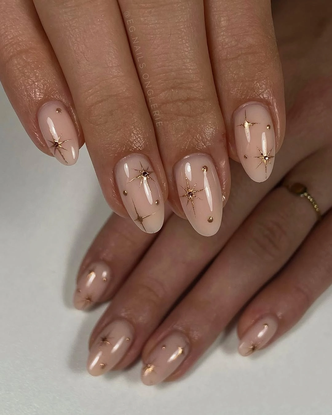 Short nude almond nails with fine dark linear marks and dots