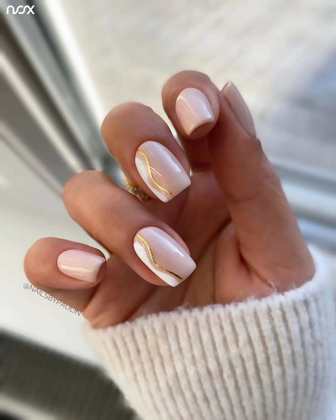 Pink nude almond nails with white curves and small warm accents