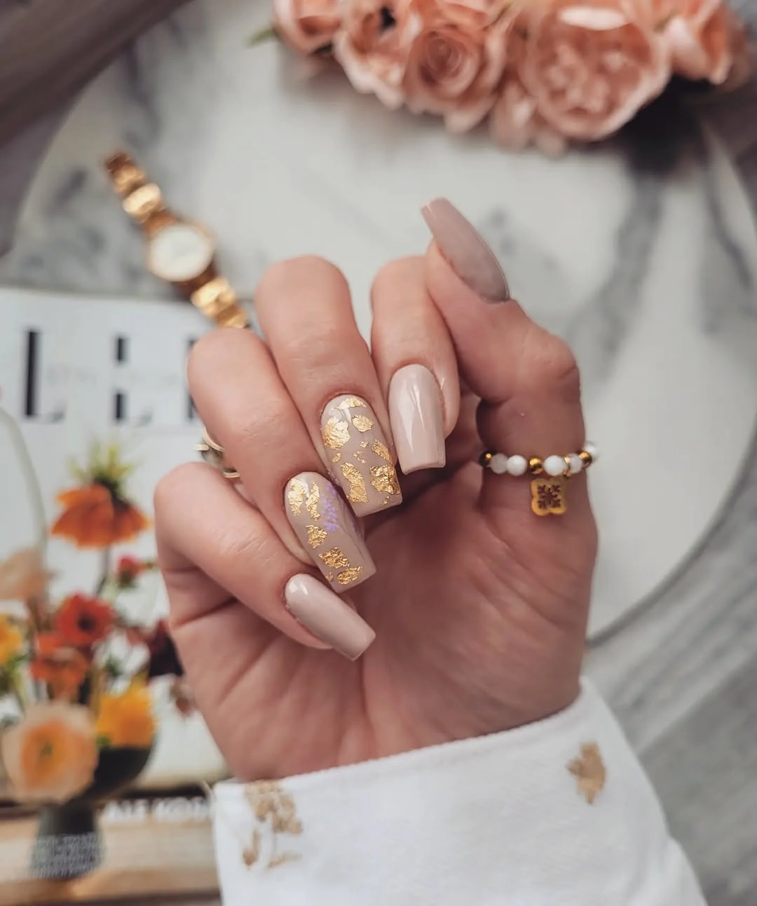 Medium nude square nails with pale sparkle and warm leaf-like accents