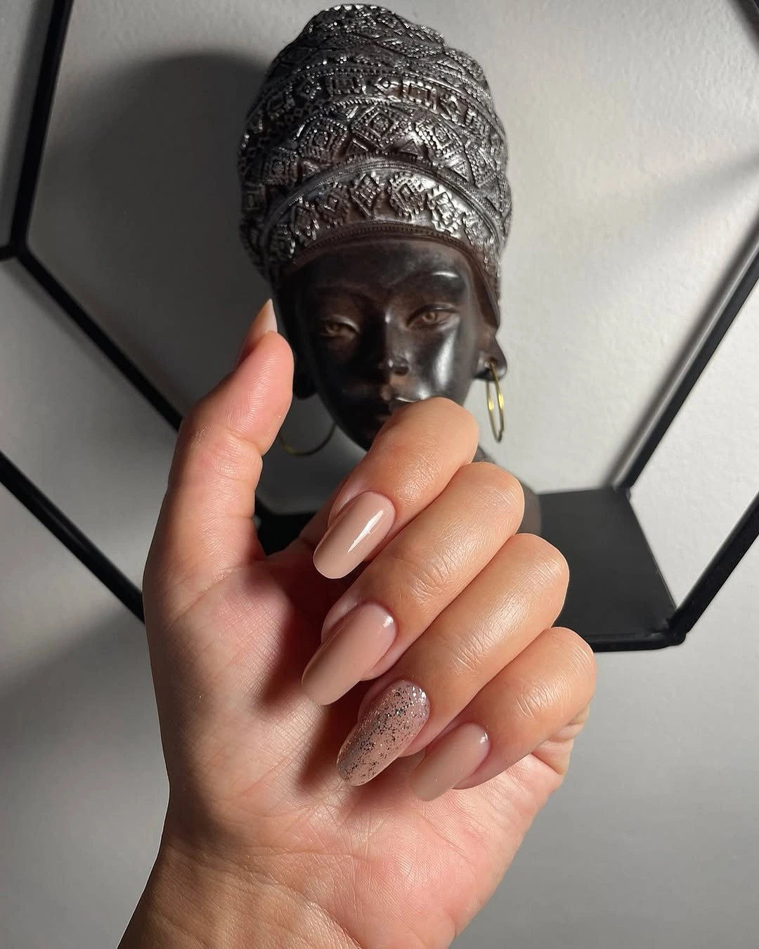 Warm tan nude almond nails with one pale sparkly accent