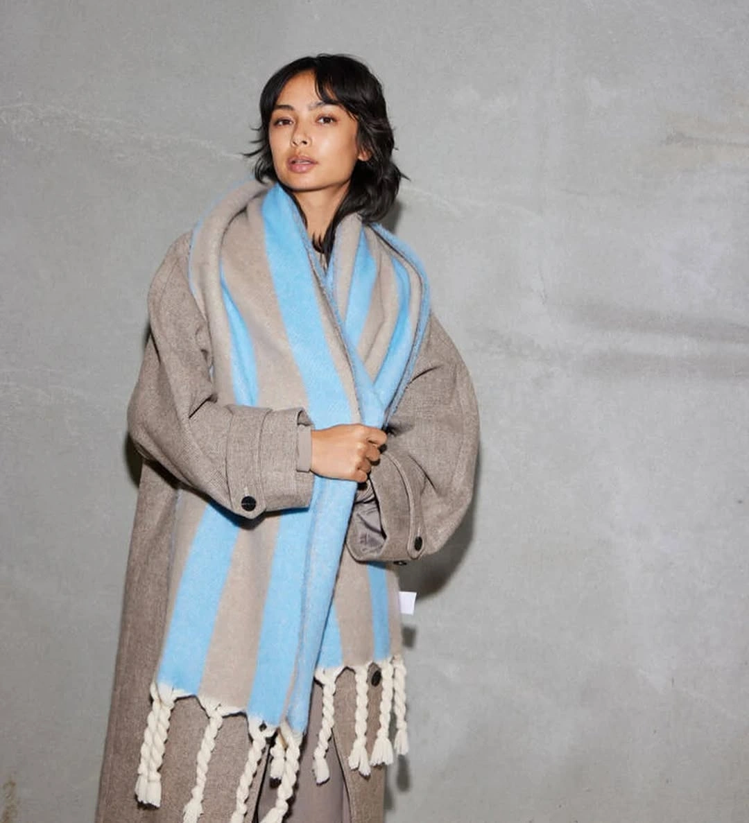 Taupe coat with oversized pale blue striped scarf and tassel detail