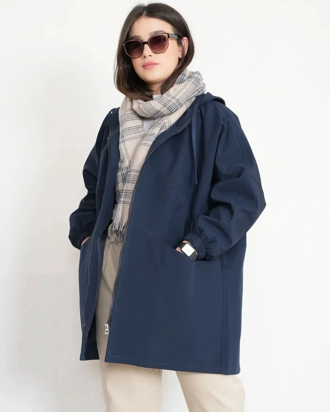 Navy hooded jacket with beige checked scarf neutral trousers and sunglasses