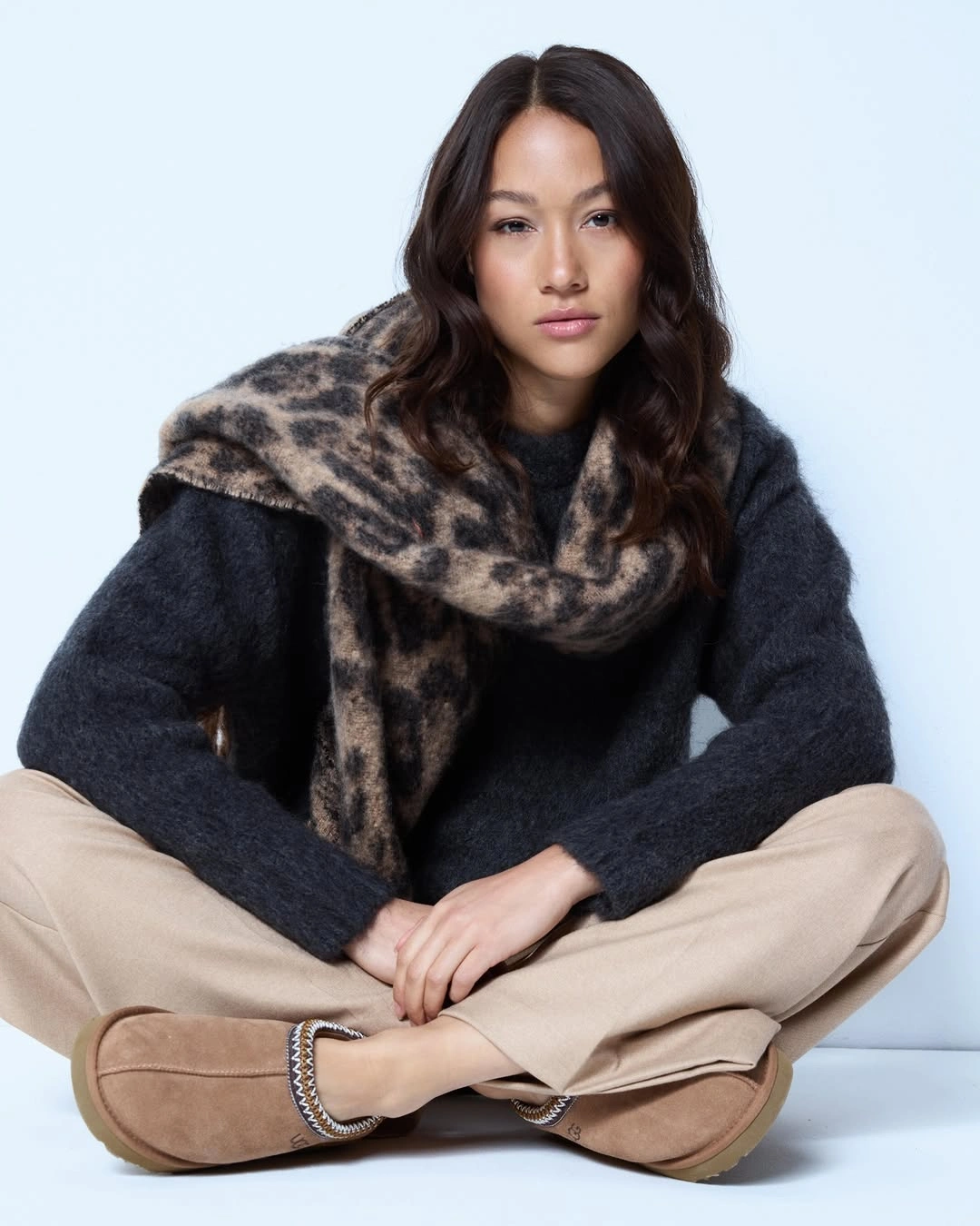 Charcoal sweater beige trousers and oversized animal-print scarf with tan slip-on shoes