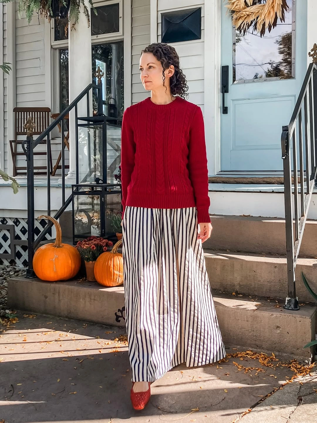 Red cable sweater with striped wide-leg trousers and red flats