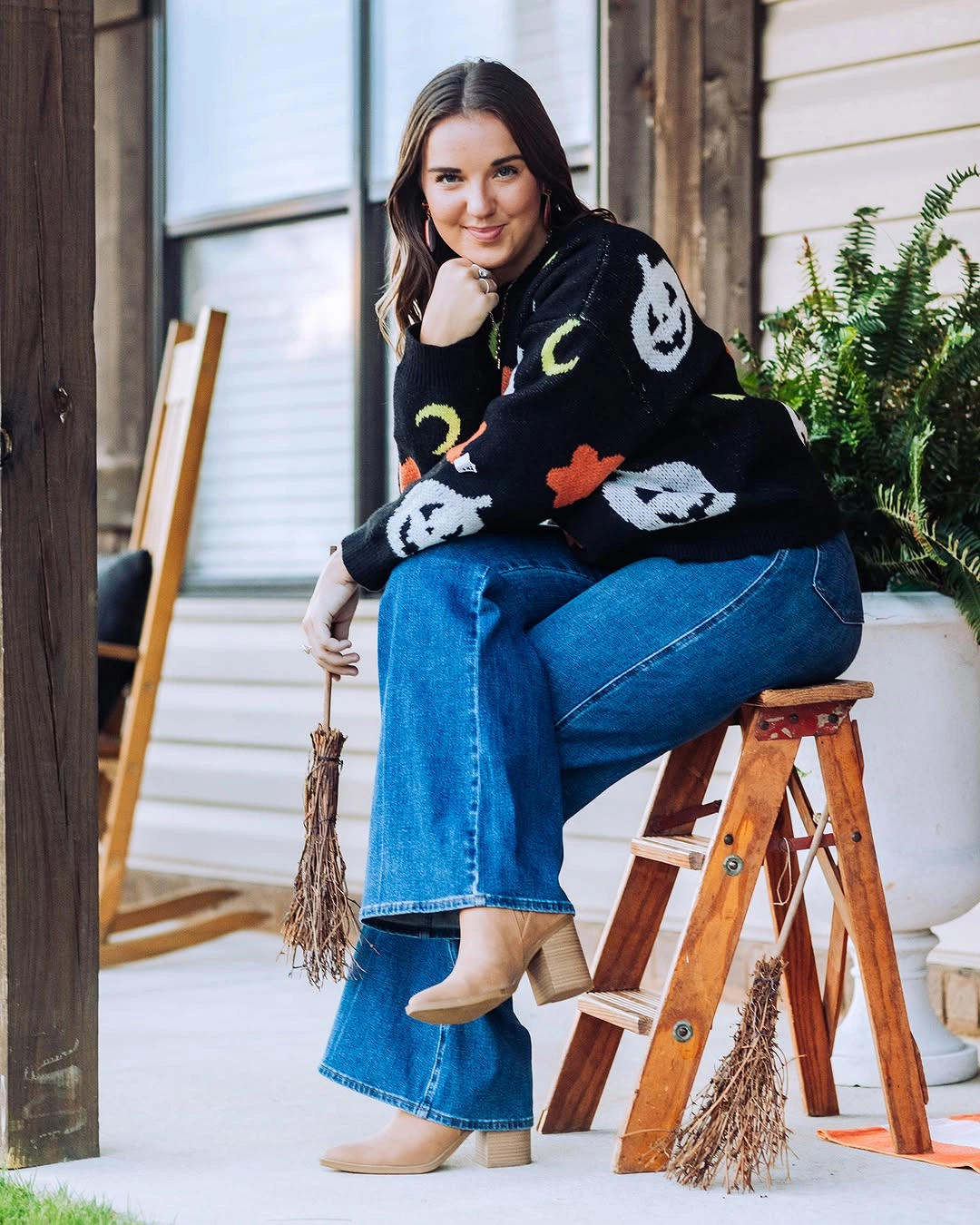 Black novelty sweater with blue flared jeans and cream ankle boots