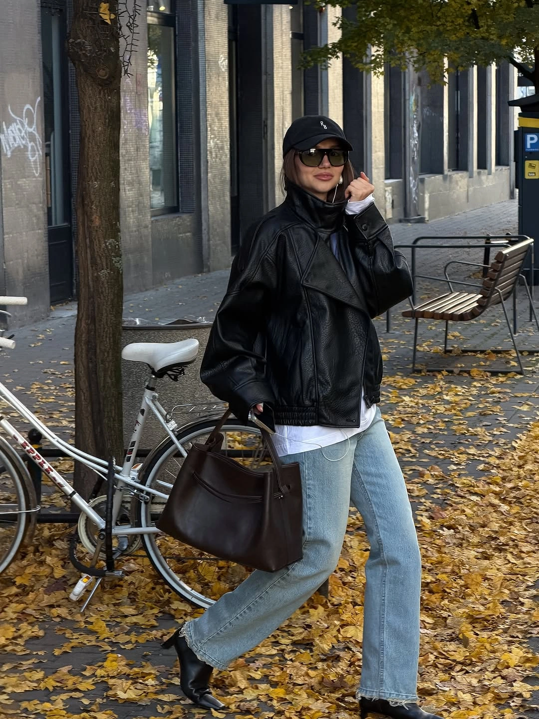 Black oversized jacket with pale denim cap and dark brown tote