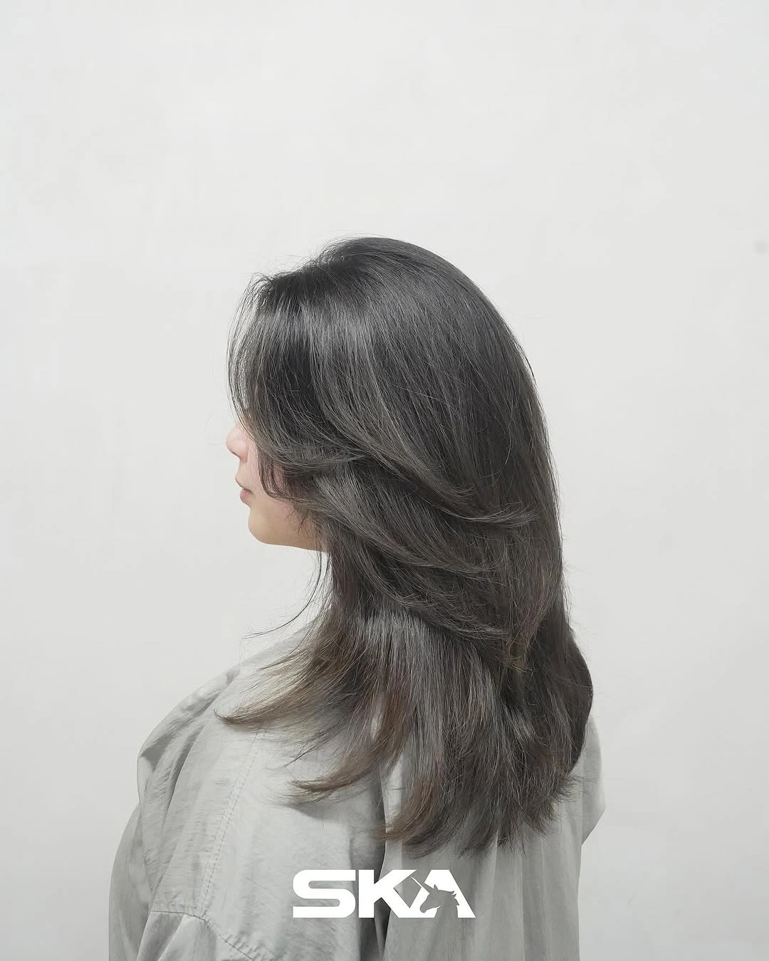 Soft black shoulder-length hair with feathered layers and airy ends