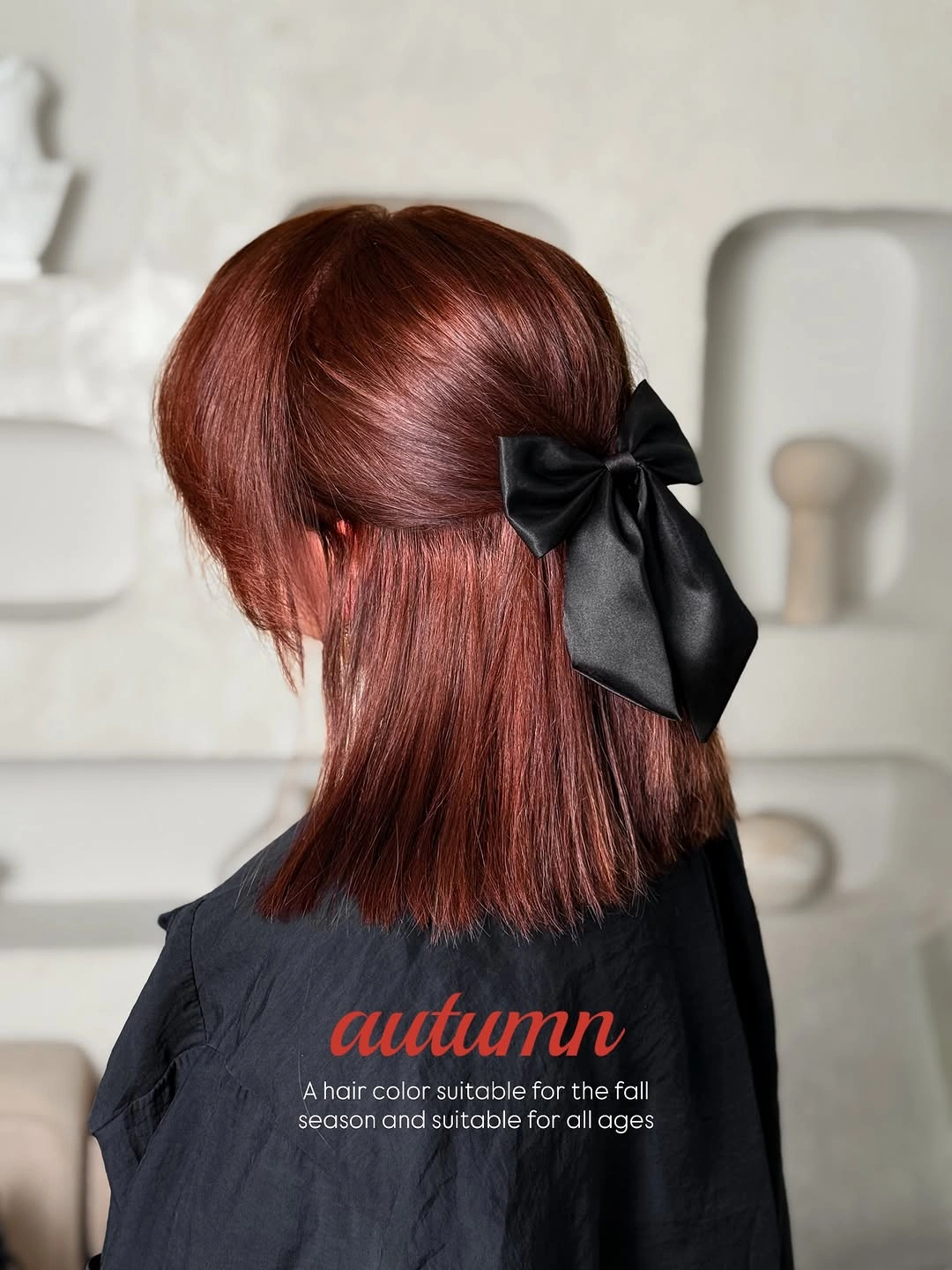 Deep auburn-brown half-up hair with large black satin bow