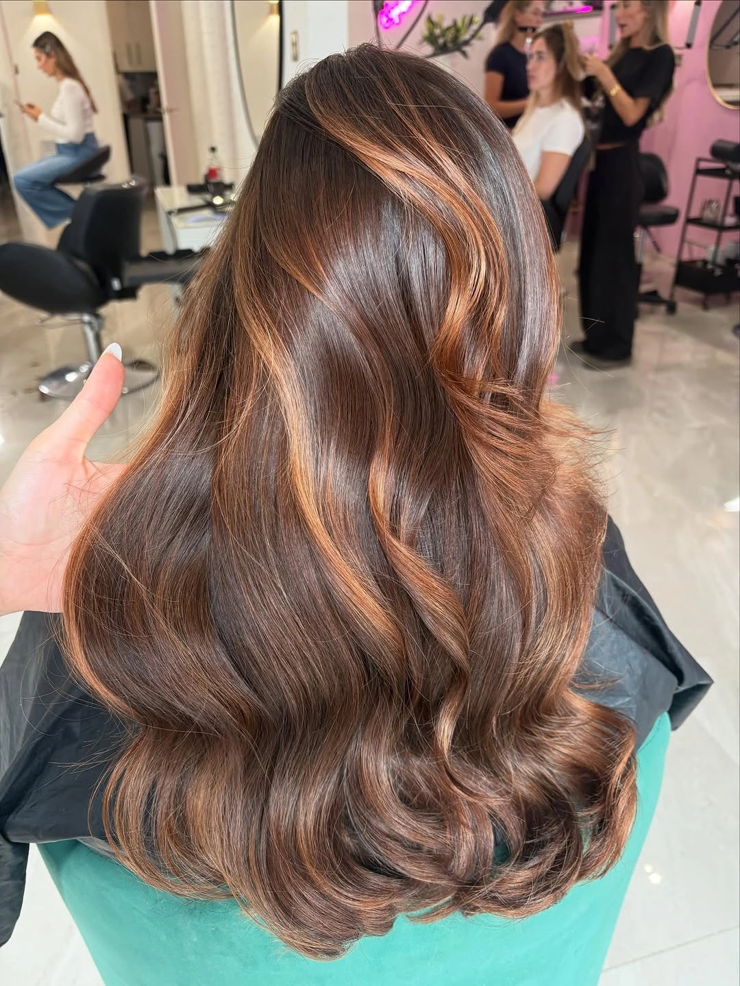 Long dark brunette waves with broad caramel ribbons and glossy finish