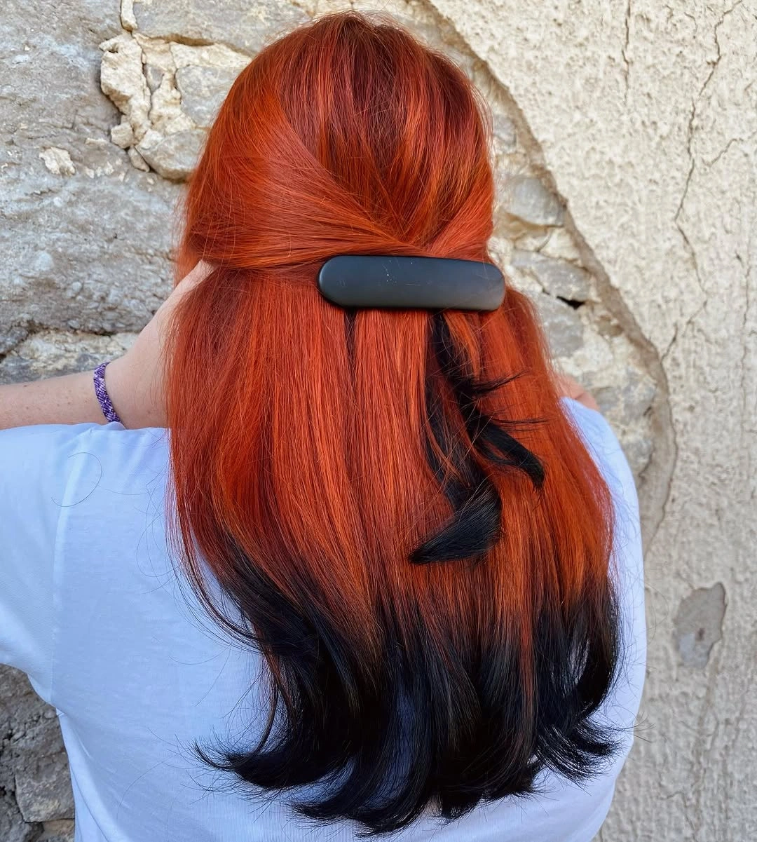 Vivid copper-red hair with dark ends and a black half-up barrette