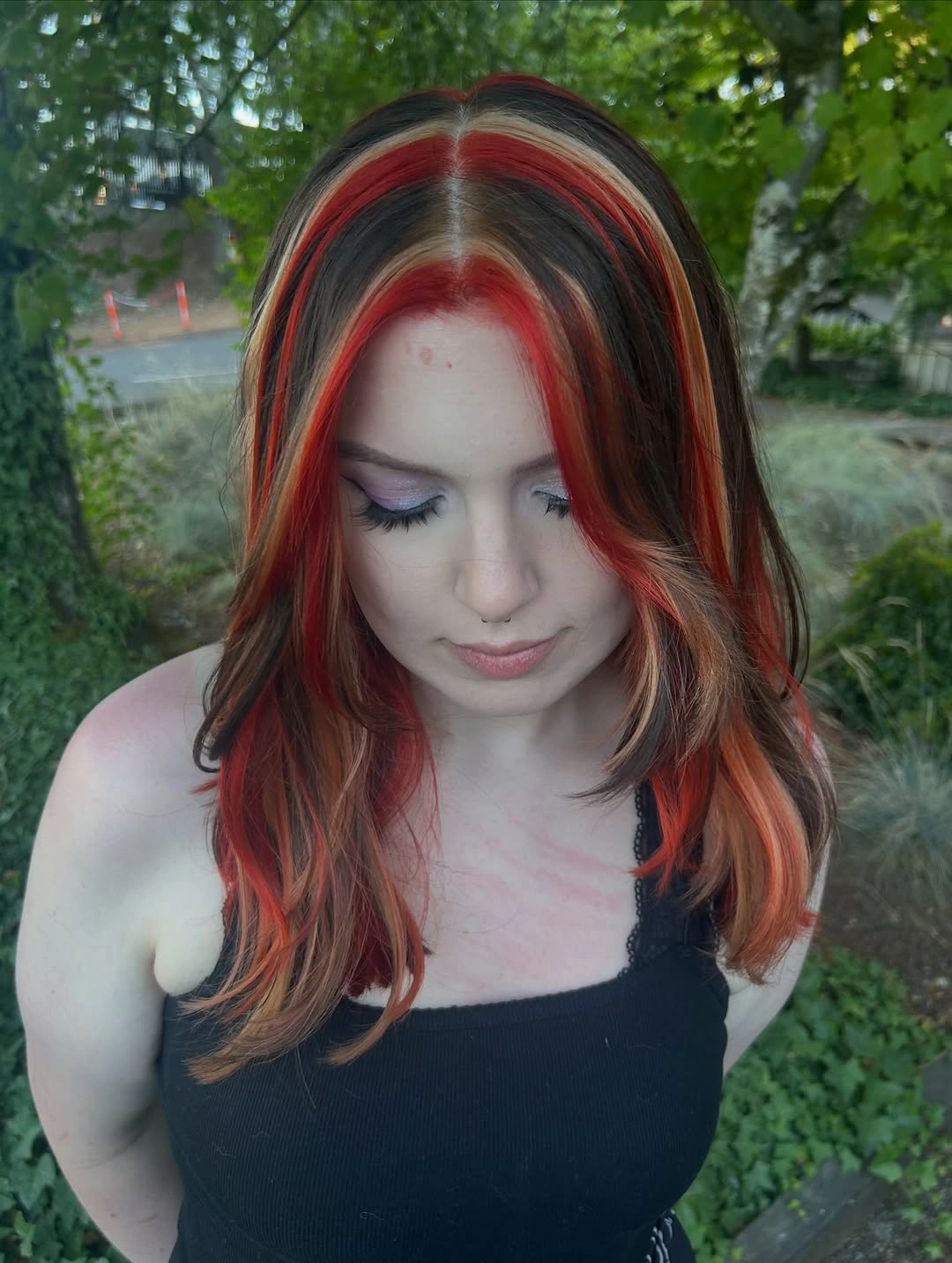 Long brunette layers with bold red face-framing panels and warm blonde ribbons