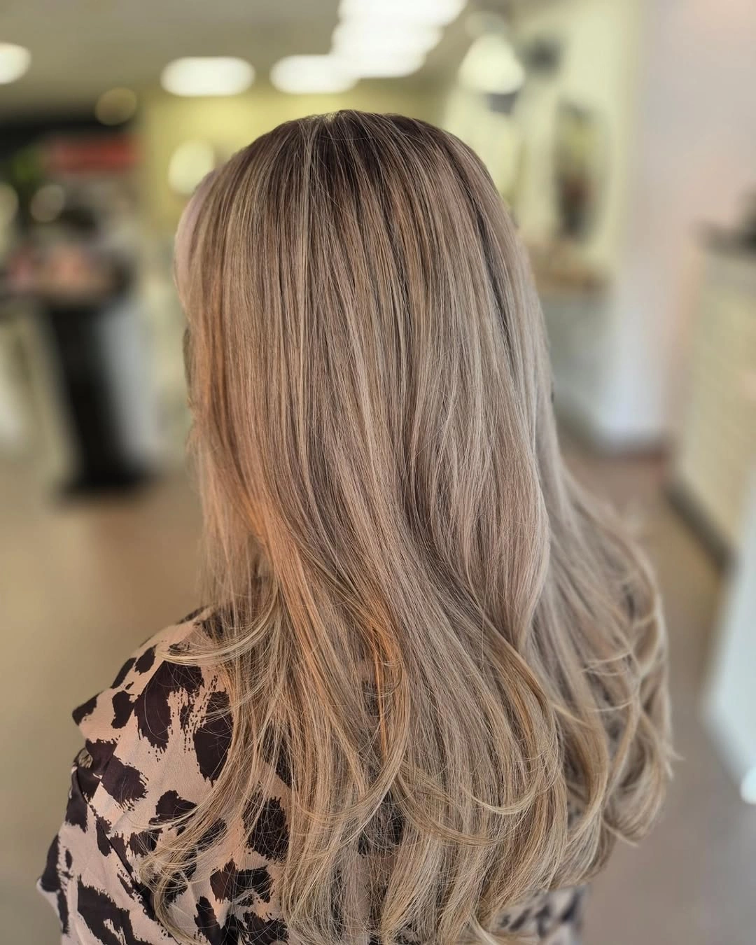 Long ash-beige blonde waves with muted root and fine blended ribbons