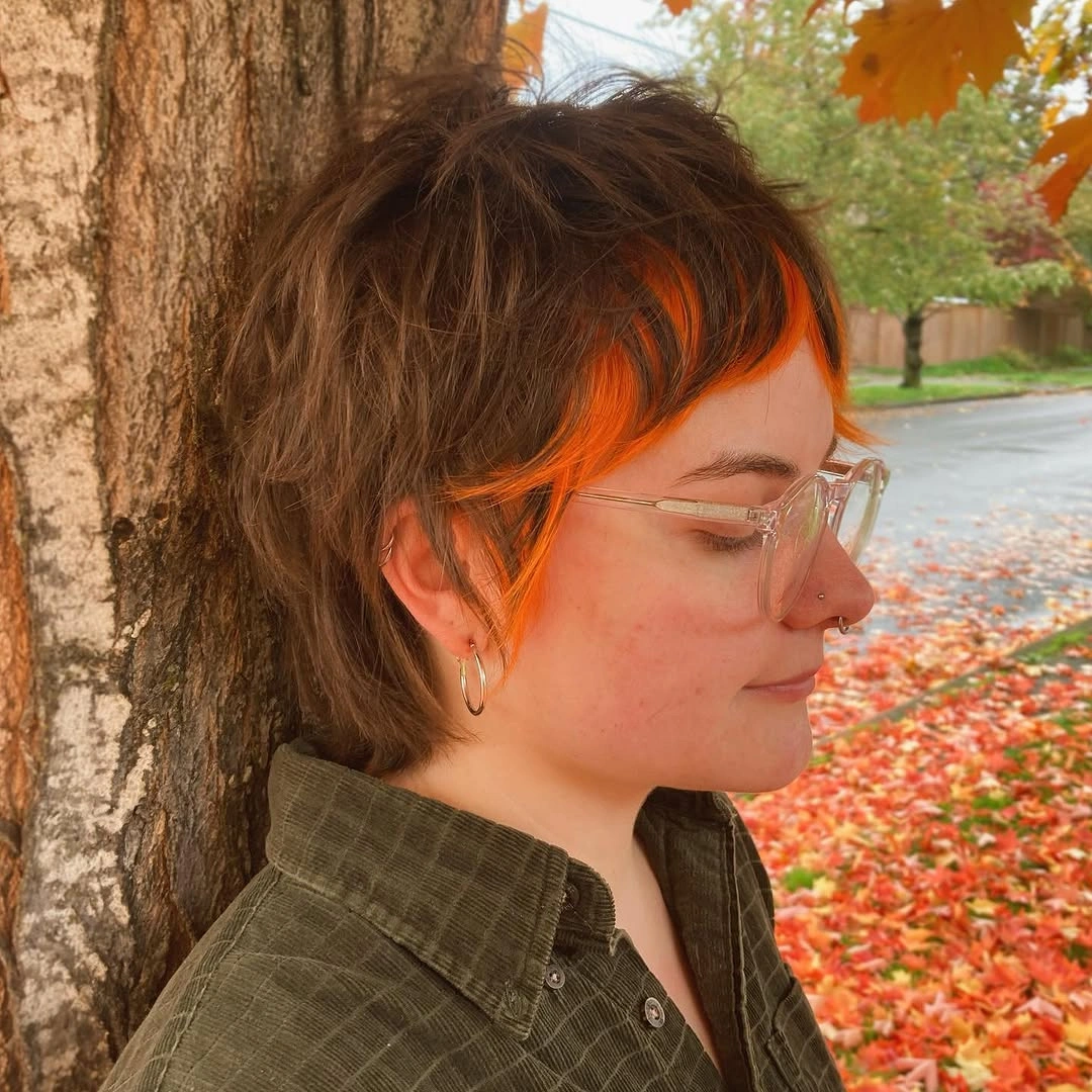 Short shaggy brown haircut with textured crown and bright orange front pieces