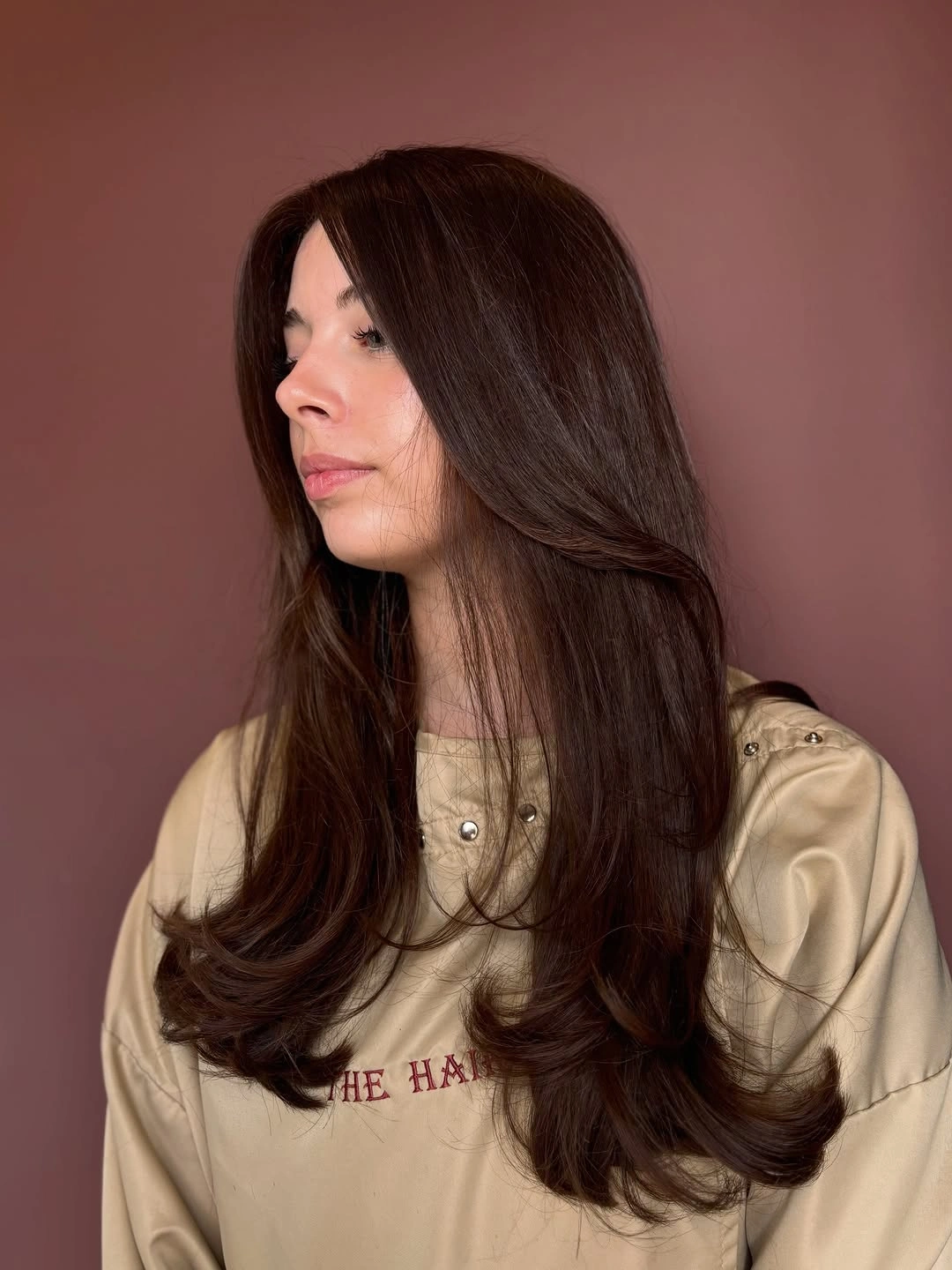 Long dark brown hair with middle part, long layers, and outward-curled ends