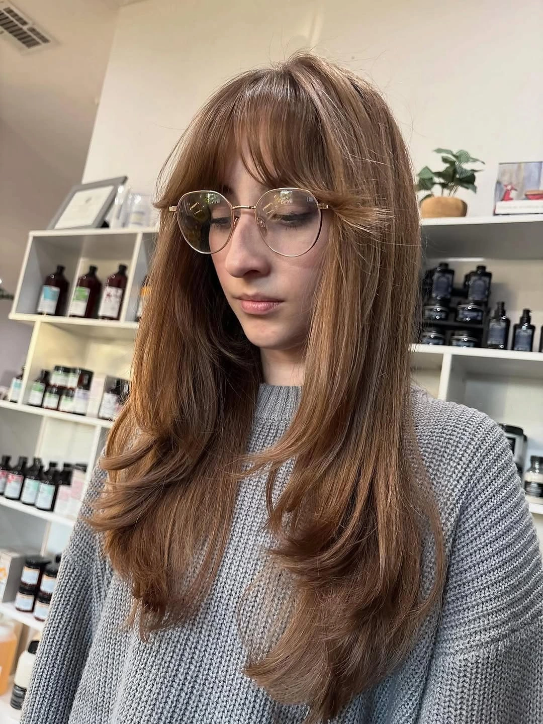 Long warm light-brown hair with wispy fringe, layers, and flicked ends