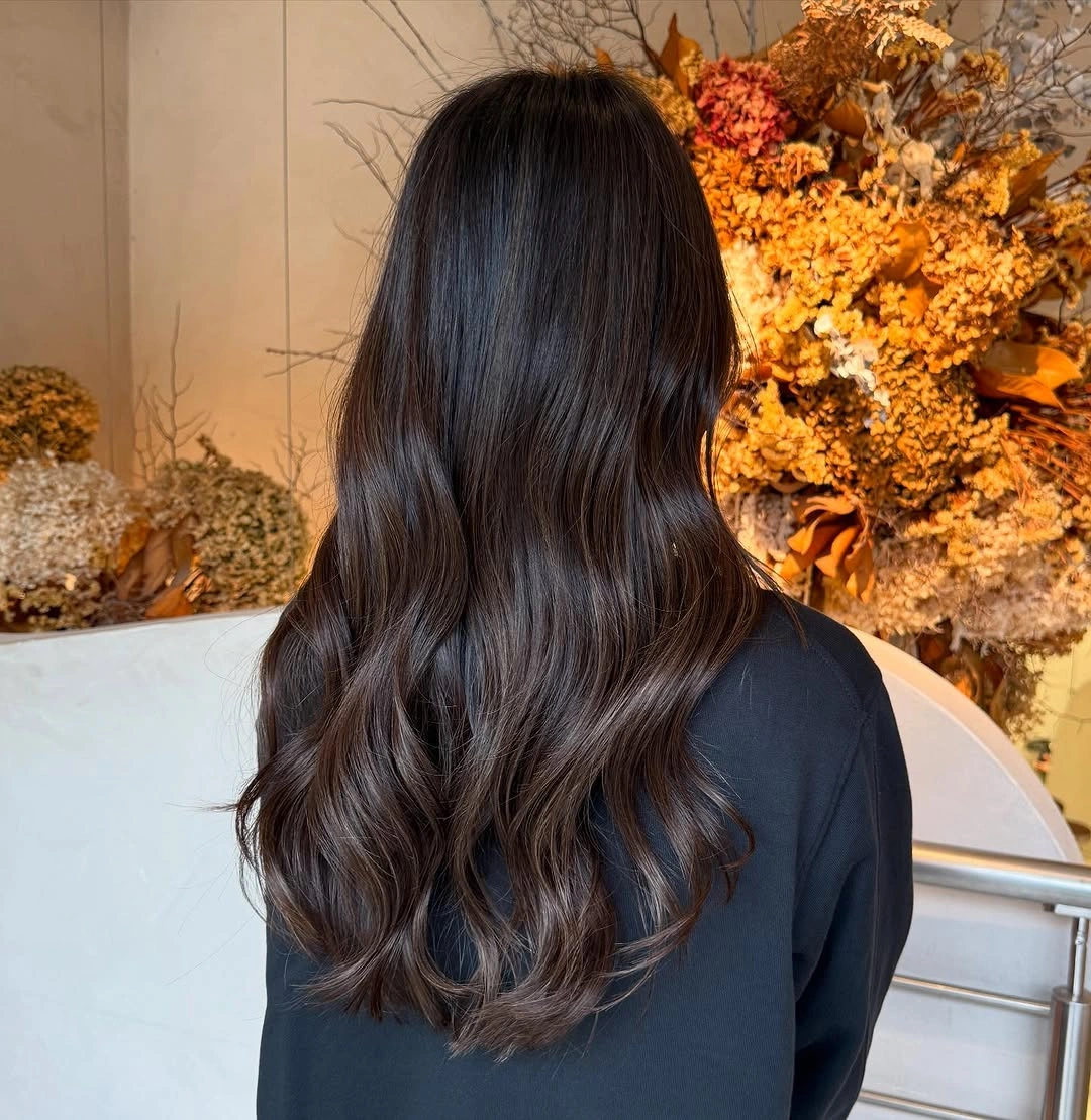 Long near-black hair with broad waves and rounded lower ends