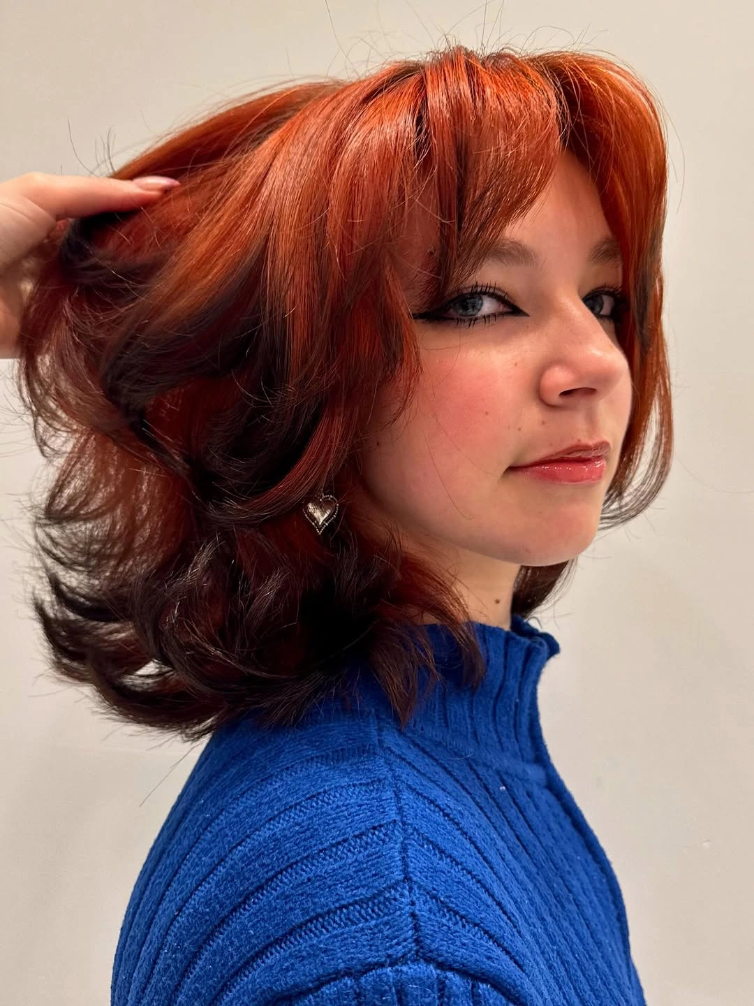 Medium-long copper-red hair with side-swept fringe and flipped curled ends