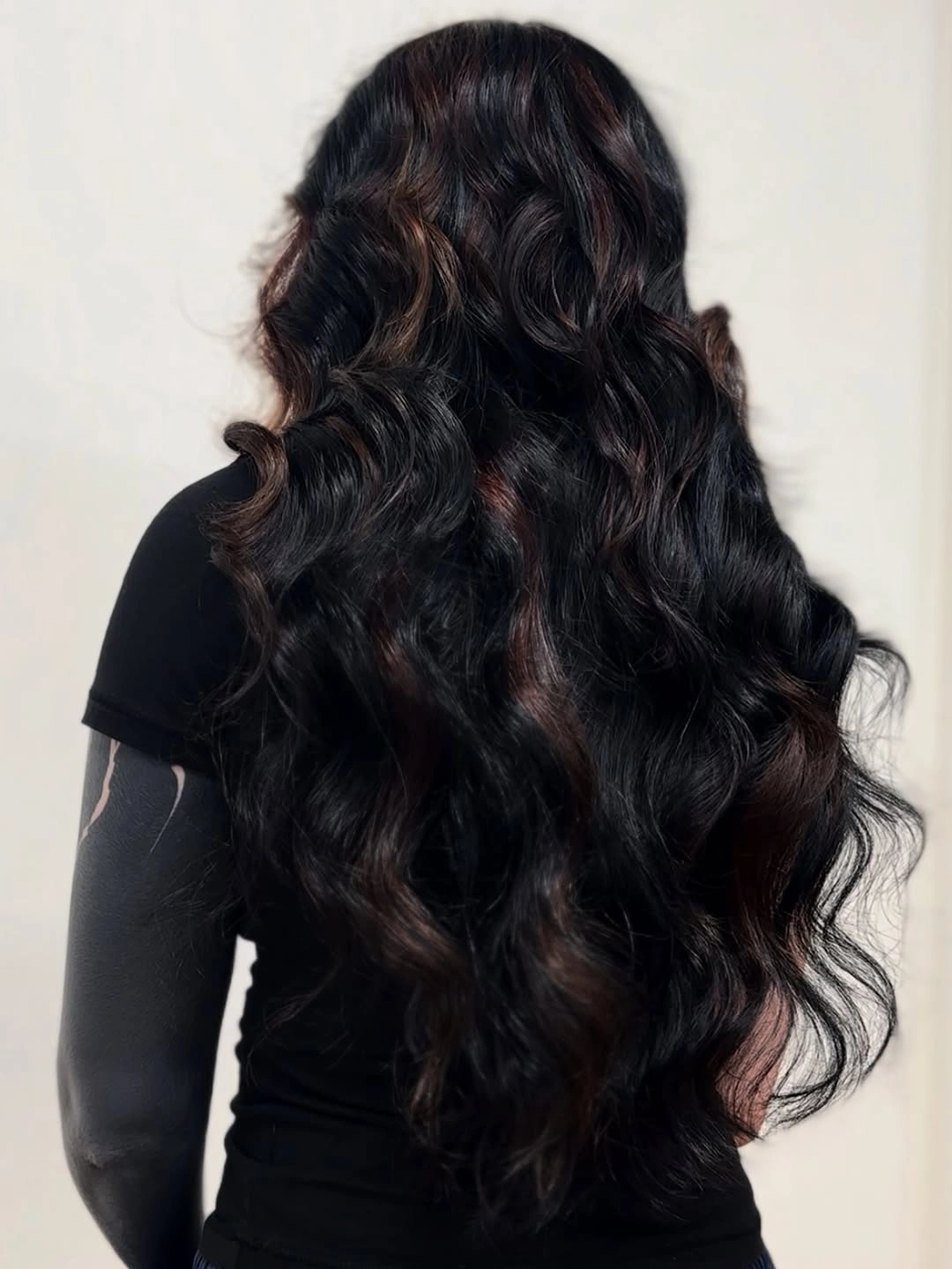 Very long near-black hair with defined waves and subtle warm reflections