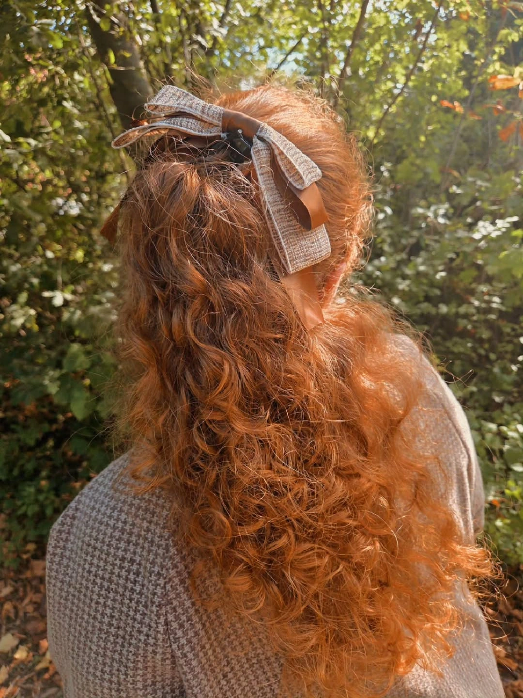 Long copper curls gathered half-up with a patterned bow at the crown