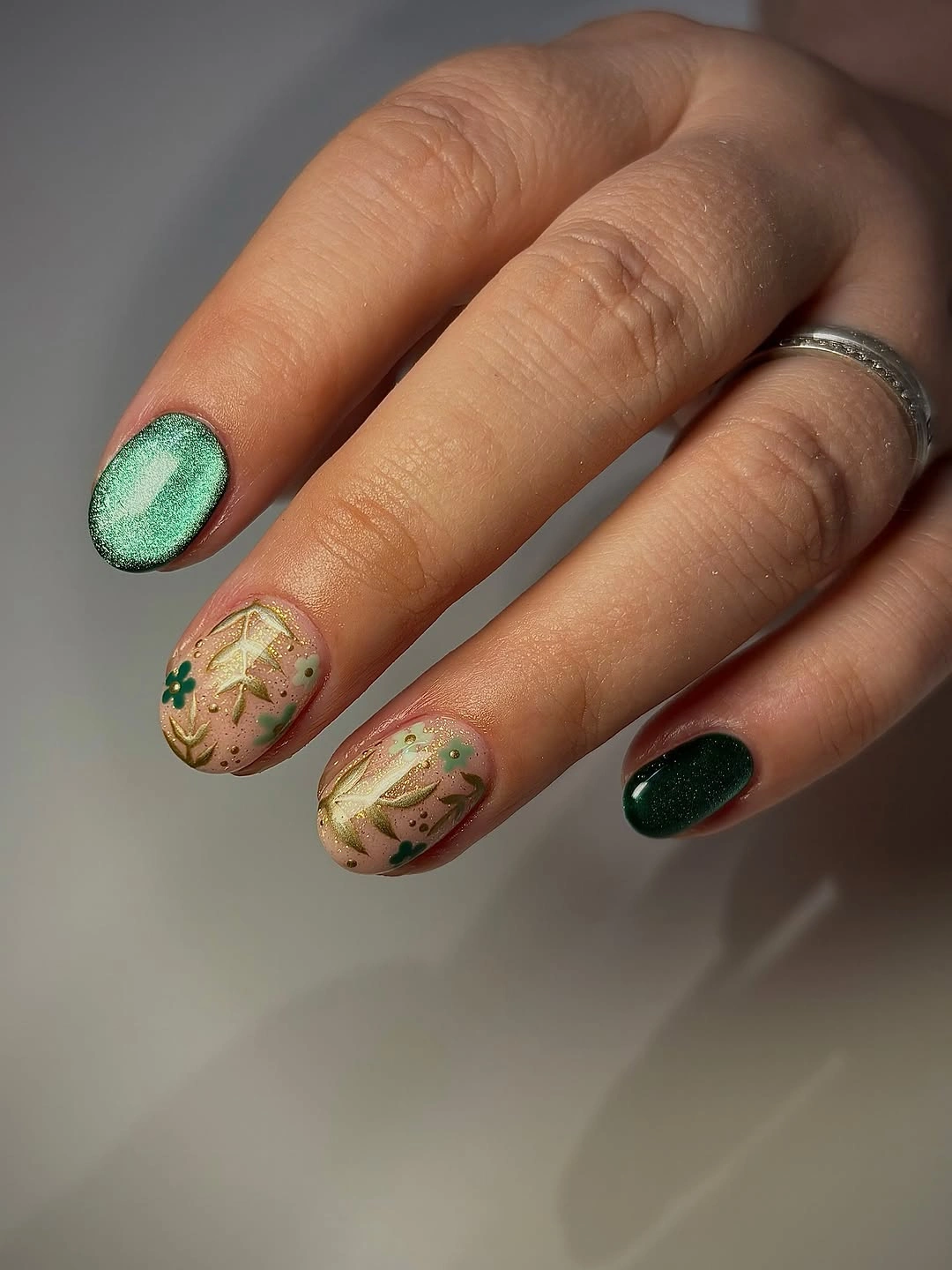 Short rounded nails in sage beige and green with fine leaf lines