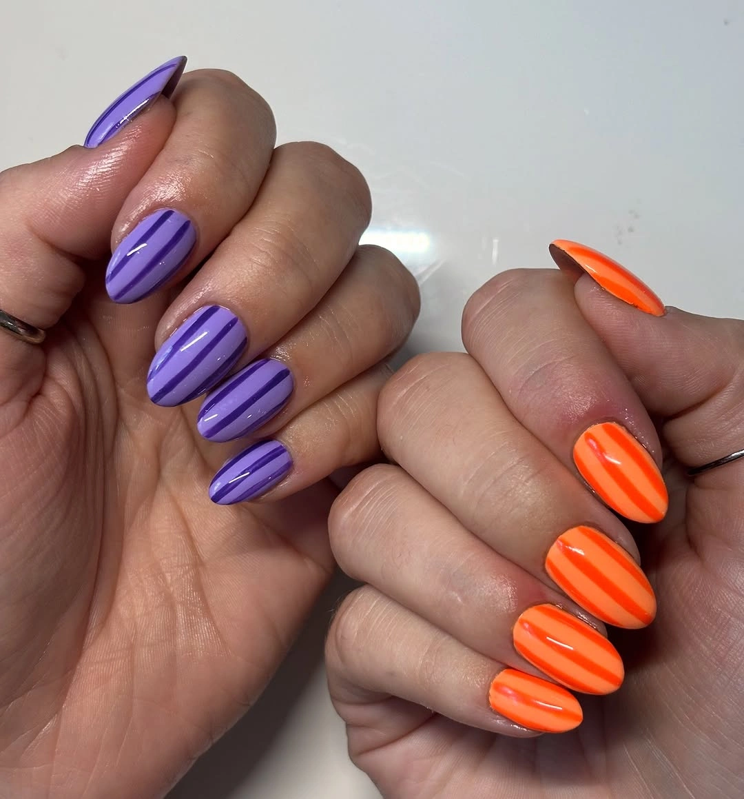 Glossy purple and bright orange medium almond nails on paired hands