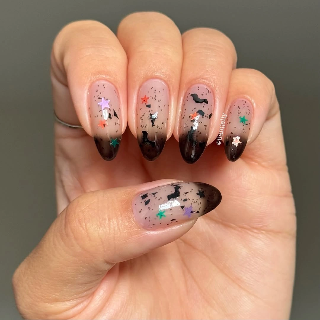 Short nude nails with smoky dark tips stars and colorful speckles