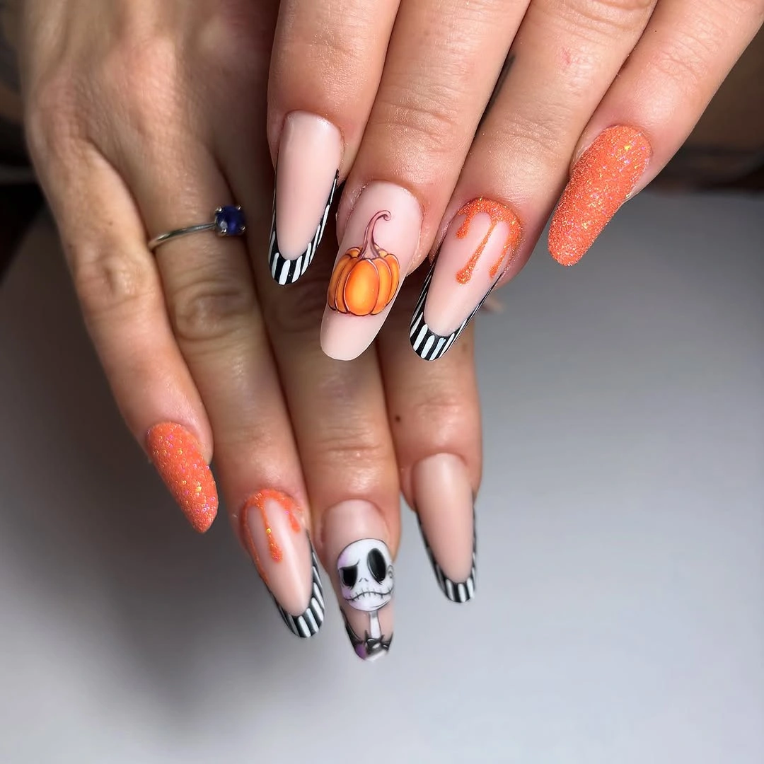 Nude almond nails with orange glitter stripes pumpkin and skull