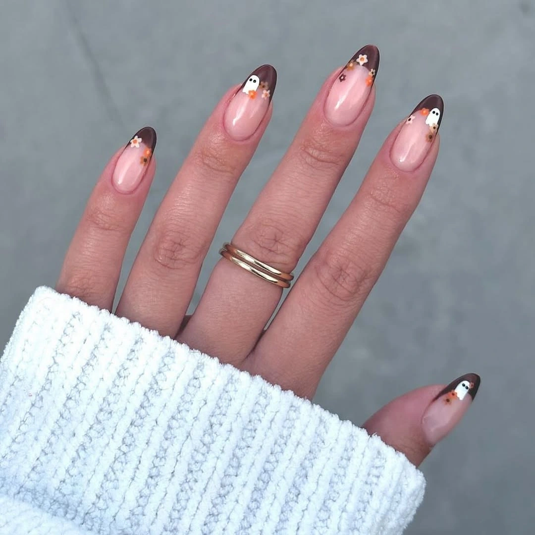 Pink almond nails with tiny white ghost faces and dark tips