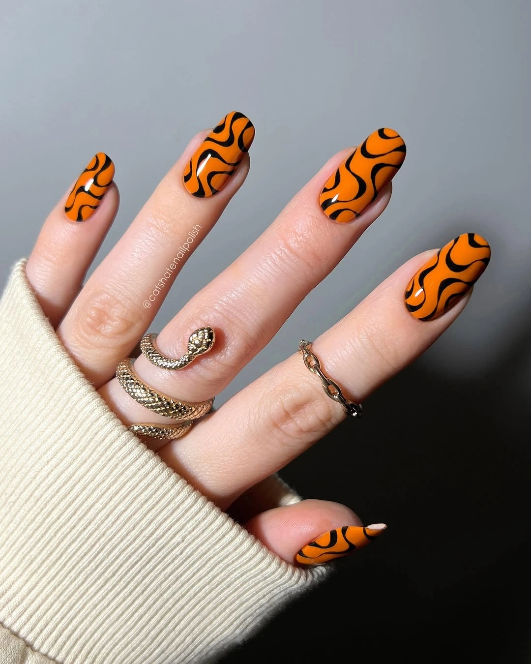 Orange almond nails with bold black wavy graphic lines