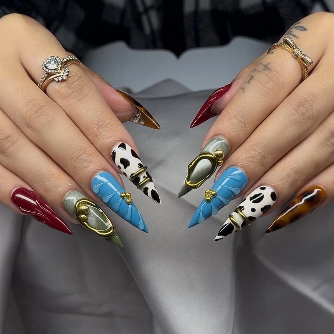 Long stiletto nails with burgundy blue cow print and gold details