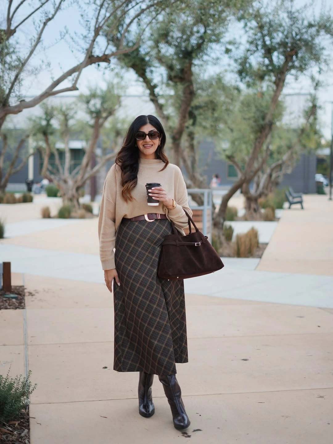 Cream sweater with brown checked midi skirt tall black boots and duffel bag