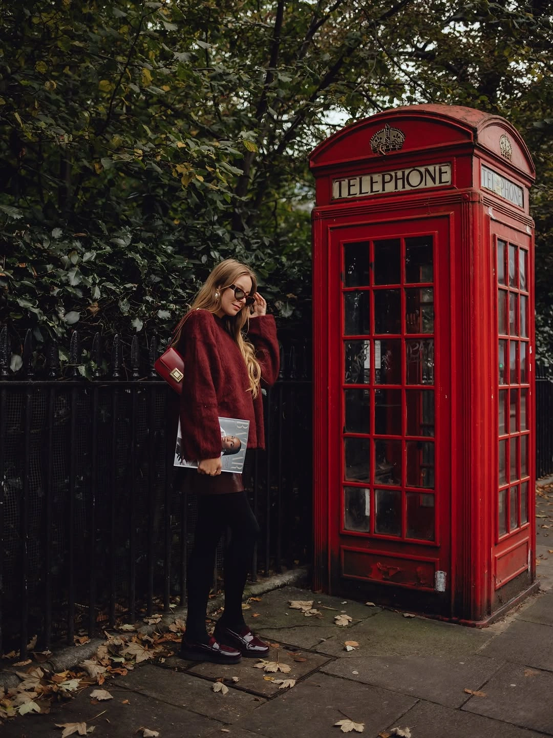 Deep burgundy textured jacket with dark short outfit black tights and pale clutch
