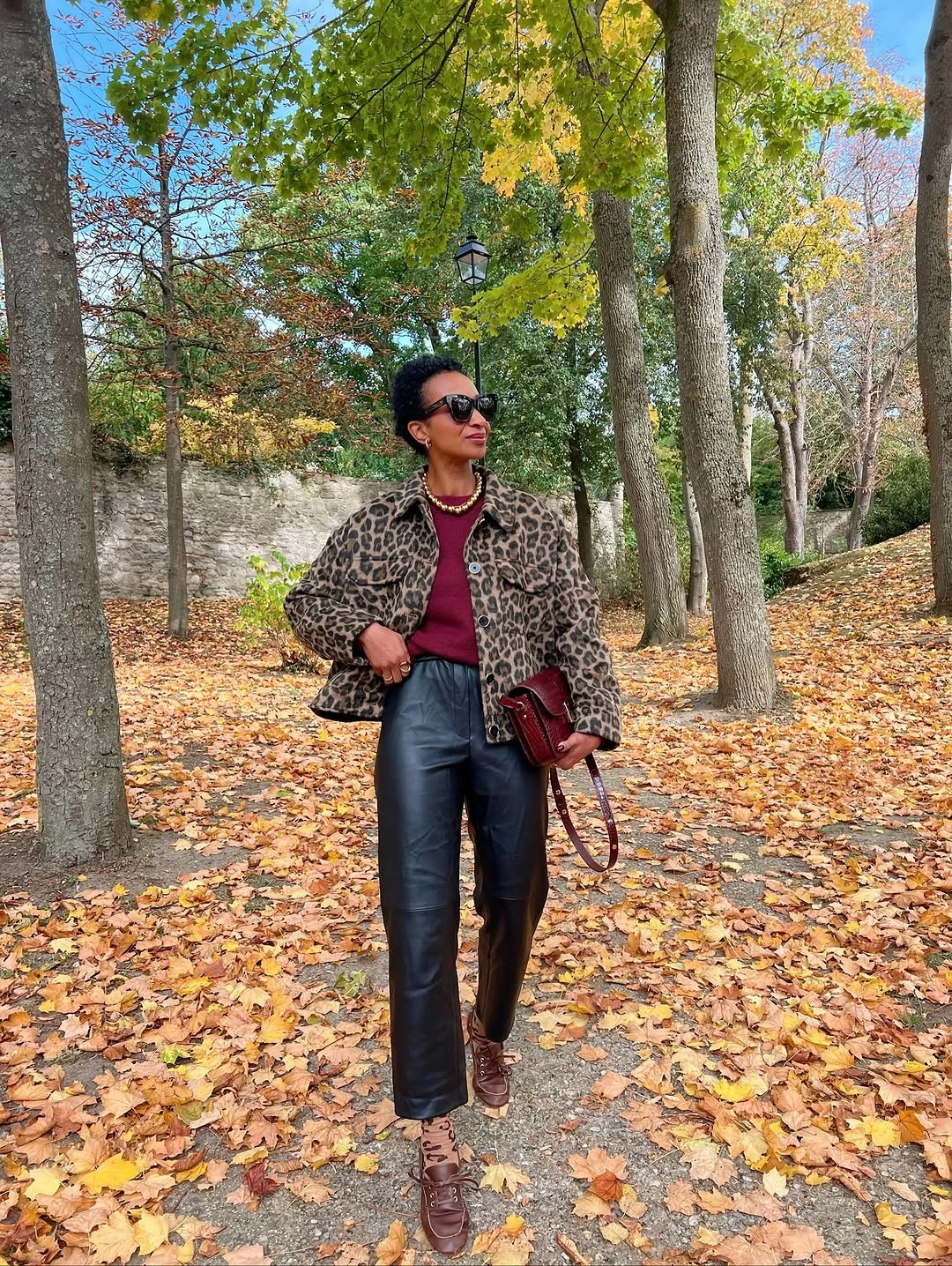 Leopard print jacket with burgundy top black trousers burgundy bag and brown shoes