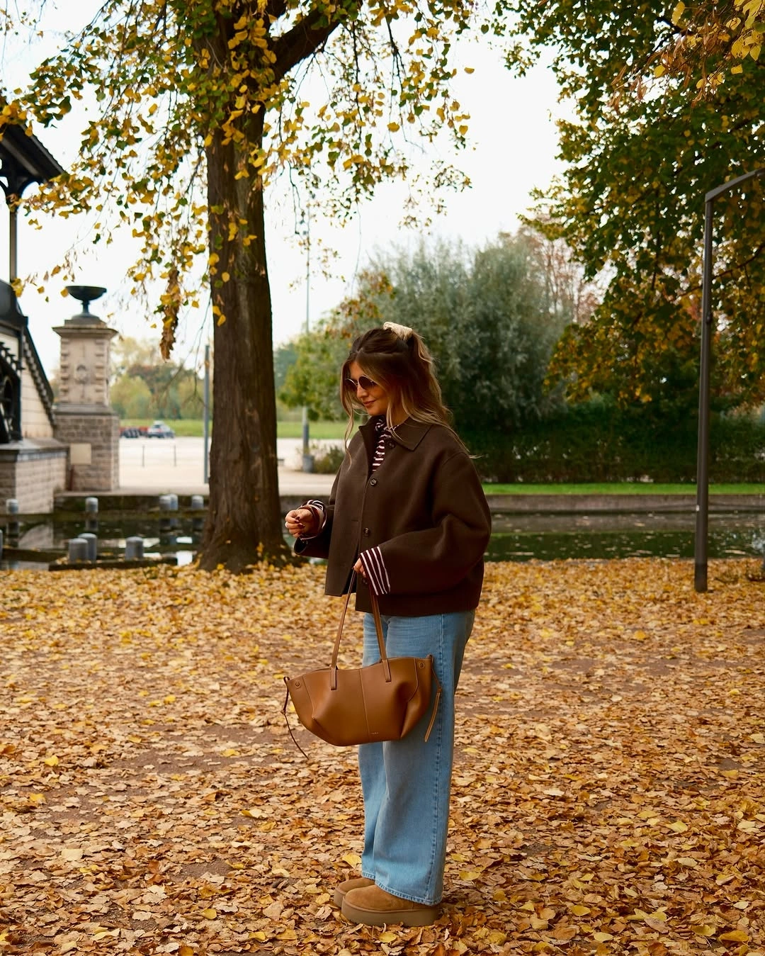 Brown cropped jacket with relaxed blue jeans and tan tote