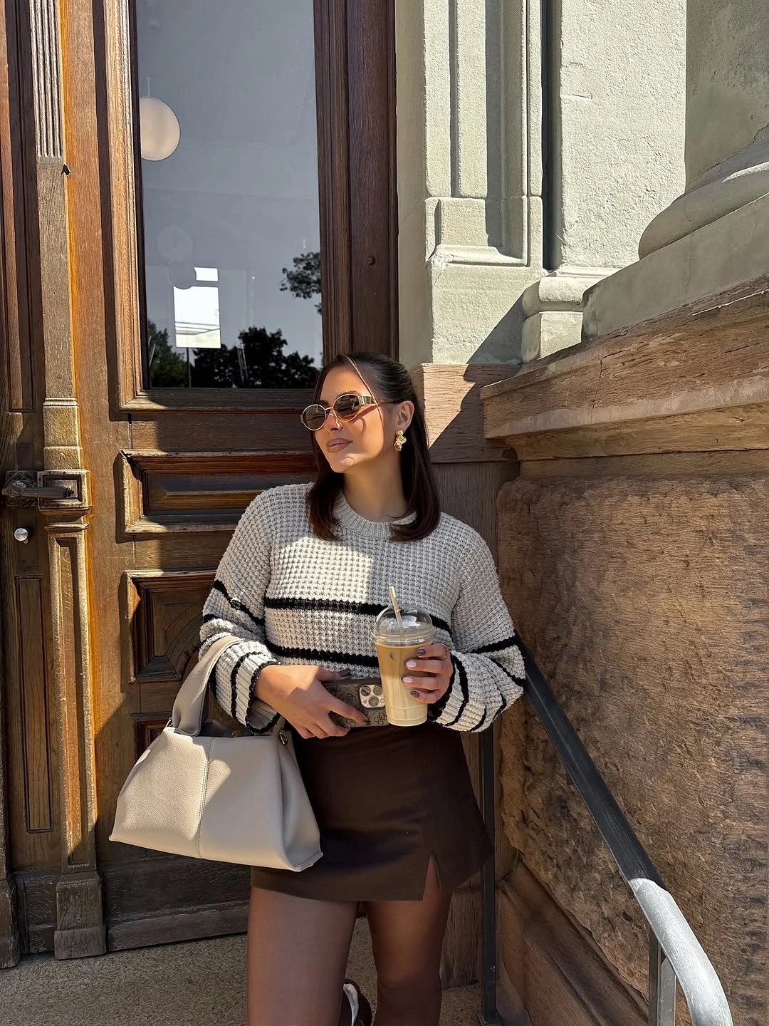 Black and white striped sweater with dark mini skirt and white bag