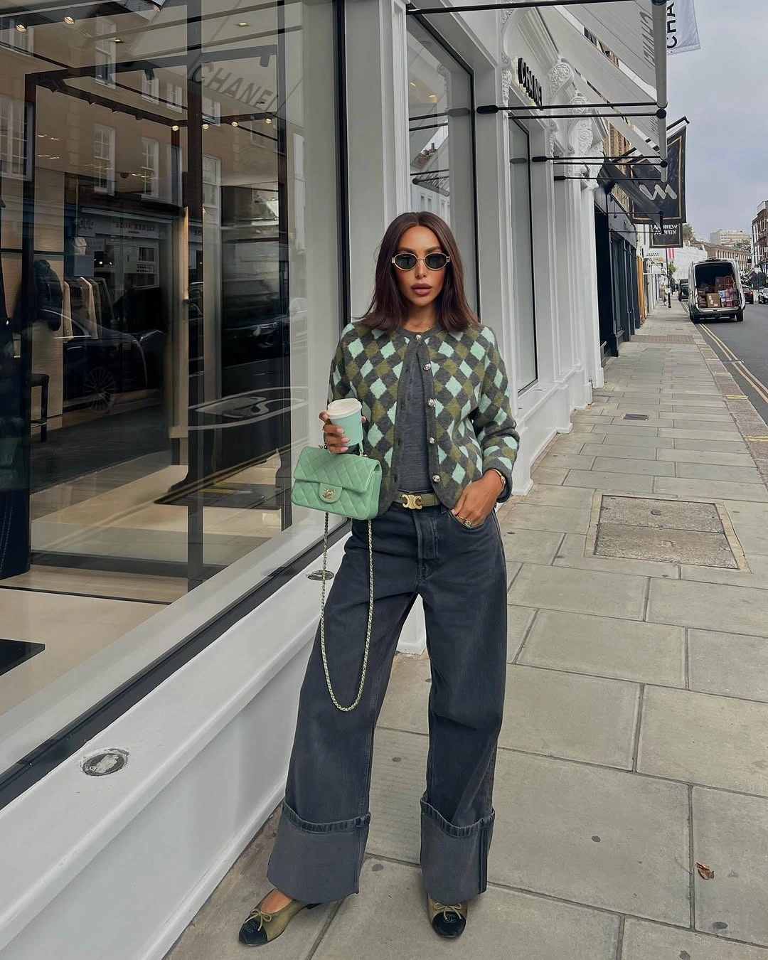 Green argyle cardigan with dark cuffed wide jeans and green bag